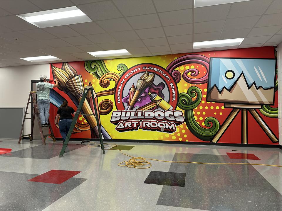 Installer applying the Bulldogs Art Room mural